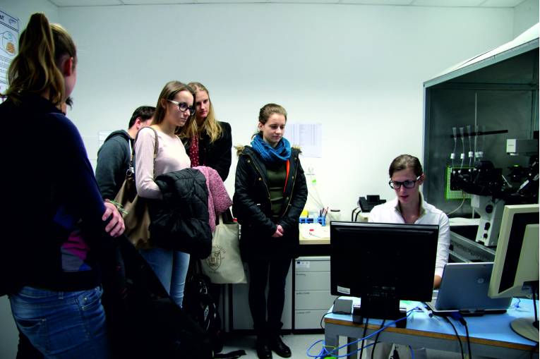 Študenti počas prehliadky laboratórií Ústavu molekulárnej fyziológie a genetiky Centra biovied SAV, vpravo RNDr. Lucia Moravčíková.