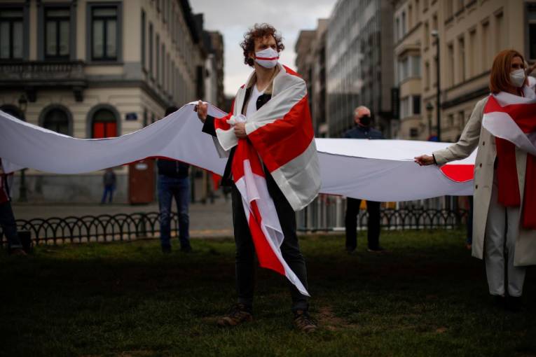 Priaznivci bieloruskej opozície držia veľkú bieloruskú historickú vlajku počas protestu pri príležitosti tzv. Dňa slobody pred Európskym parlamentom v Bruseli 25. marca 2021
