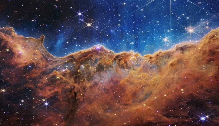 Táto krajina „hôr“ a „údolí“ posiata trblietavými hviezdami je v skutočnosti okrajom neďalekej, mladej, hviezdotvornej oblasti nazývanej NGC 3324 v hmlovine Carina. Tento obrázok, zachytený v infračervenom svetle novým vesmírnym teleskopom NASA Jamesa Webba, po prvýkrát odhaľuje predtým neviditeľné oblasti zrodu hviezd