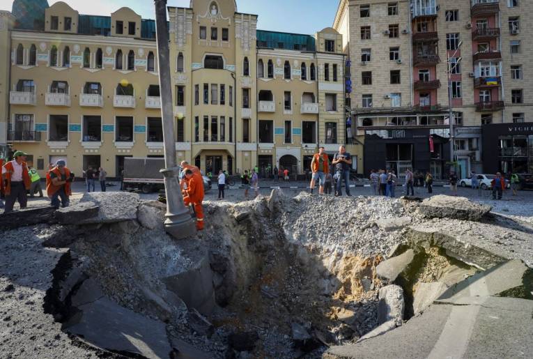 A view of a crater from a night Russian rocket attack, near to damaged buildings in downtown Kharkiv, Ukraine, Saturday, Aug. 27, 2022